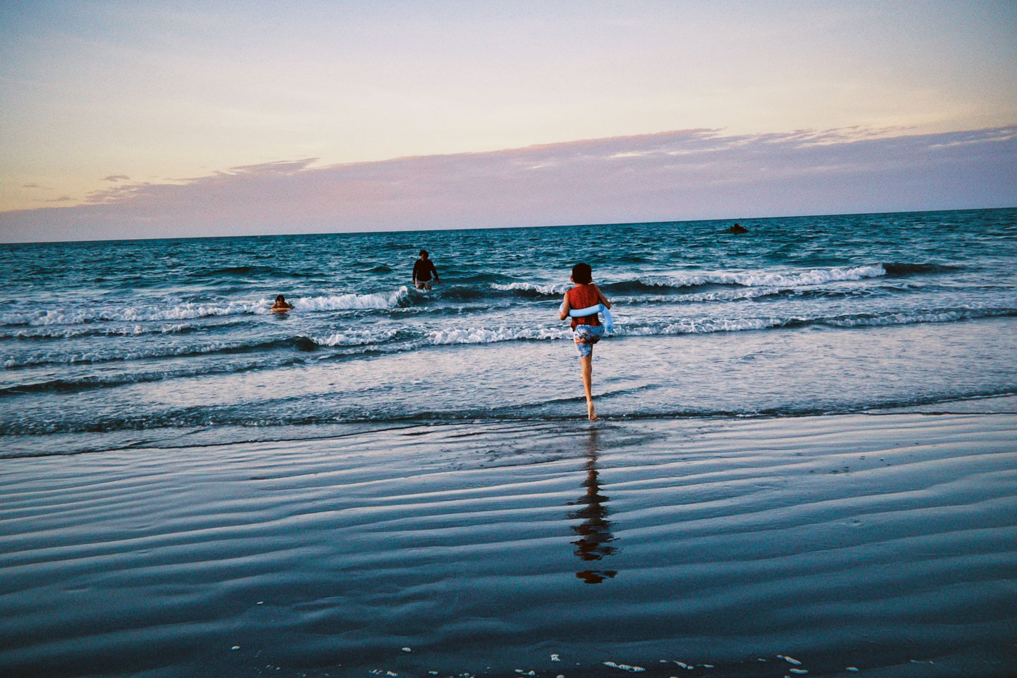 Children playing on beach at sunset during family vacation