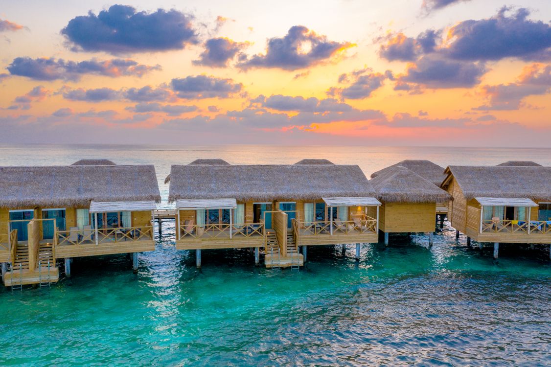 Overwater bungalows at sunrise with turquoise lagoon waters
