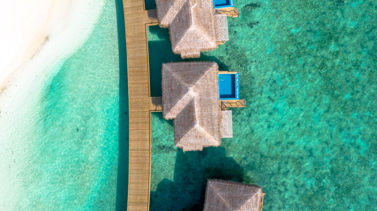 Aerial view of luxury overwater villas on crystal clear tropical waters