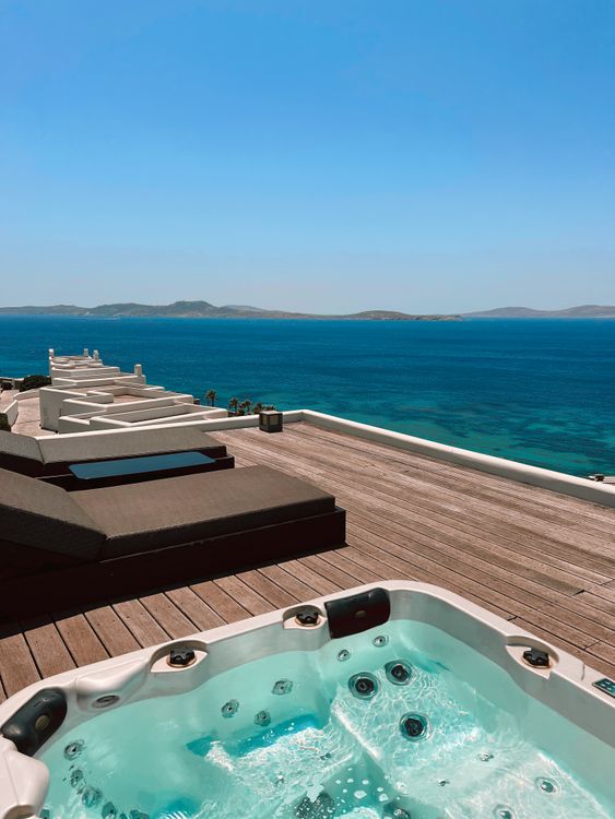 Luxurious oceanfront jacuzzi on wooden deck overlooking blue ocean