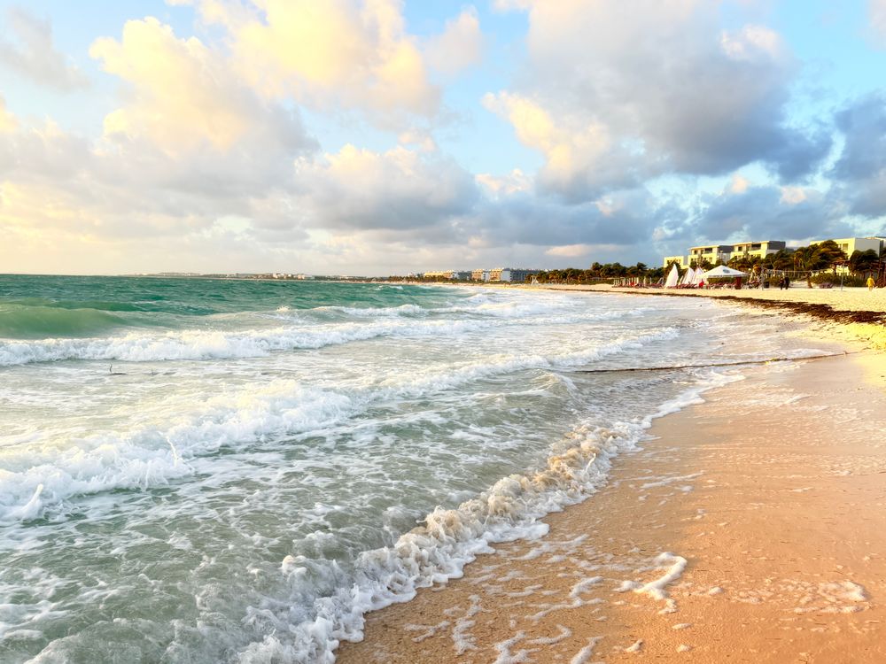Tranquil Caribbean beach at sunrise with gentle waves and vibrant sky